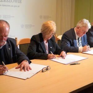 Trzy osoby podpisują porozumienie